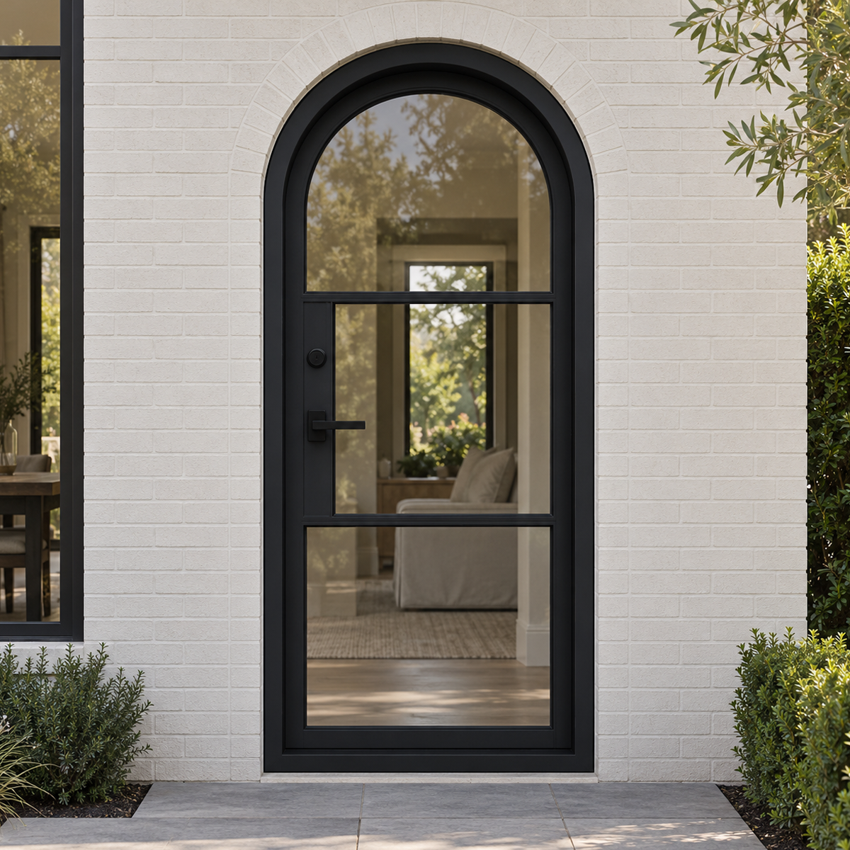Arched black iron French door installed at a modern American home entrance with light exterior walls