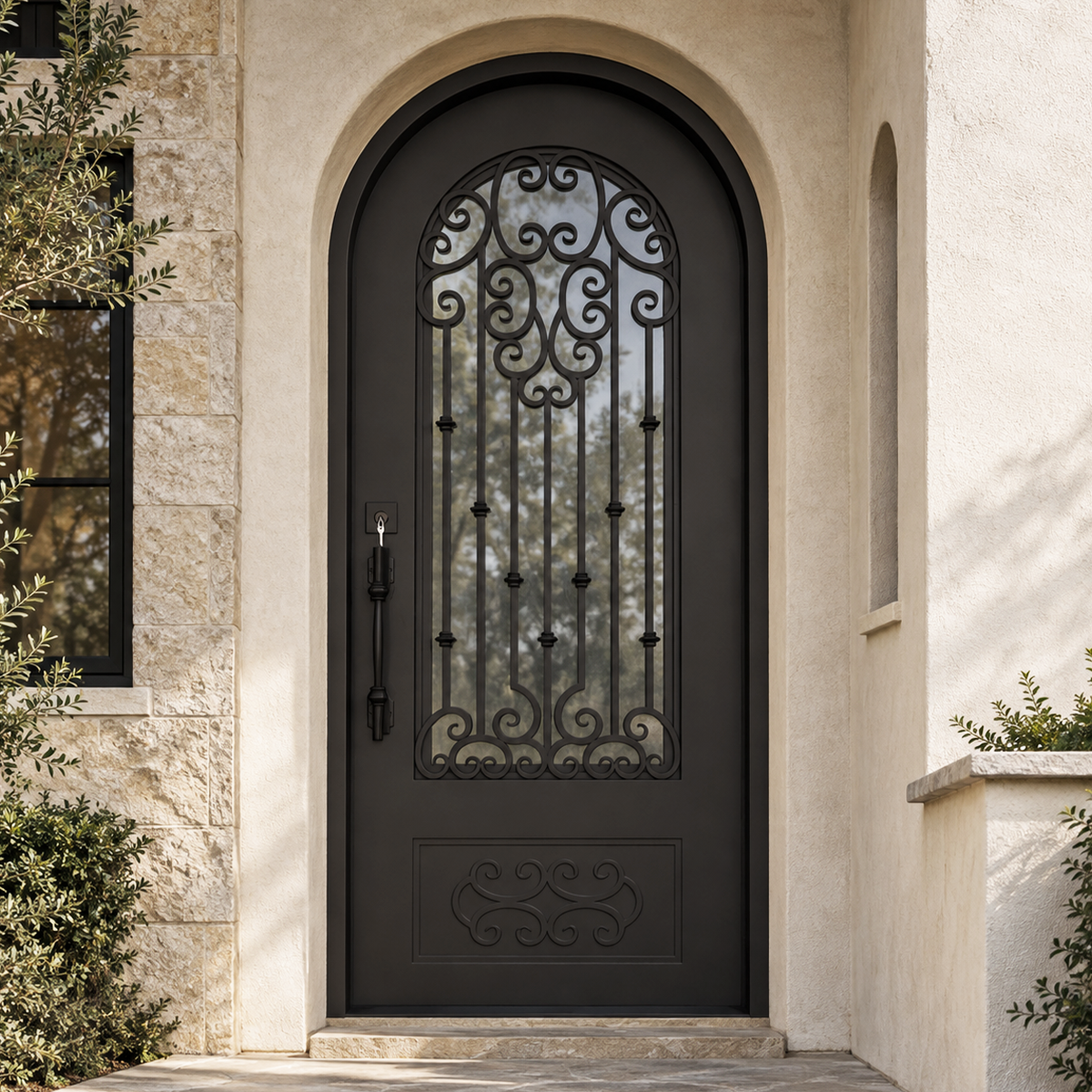 Traditional black arched iron entry door with decorative scrollwork installed at an upscale American light stone entrance
