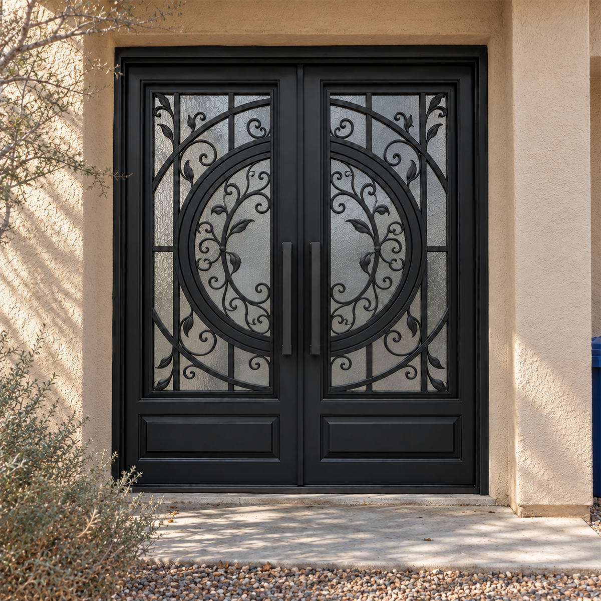 Black double traditional iron doors with a circular motif, leaf scrollwork, and textured glass in a warm stucco entrance