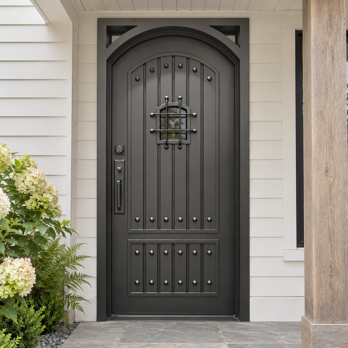 Black single traditional iron front door with decorative studs and a small grille window at a white-sided porch