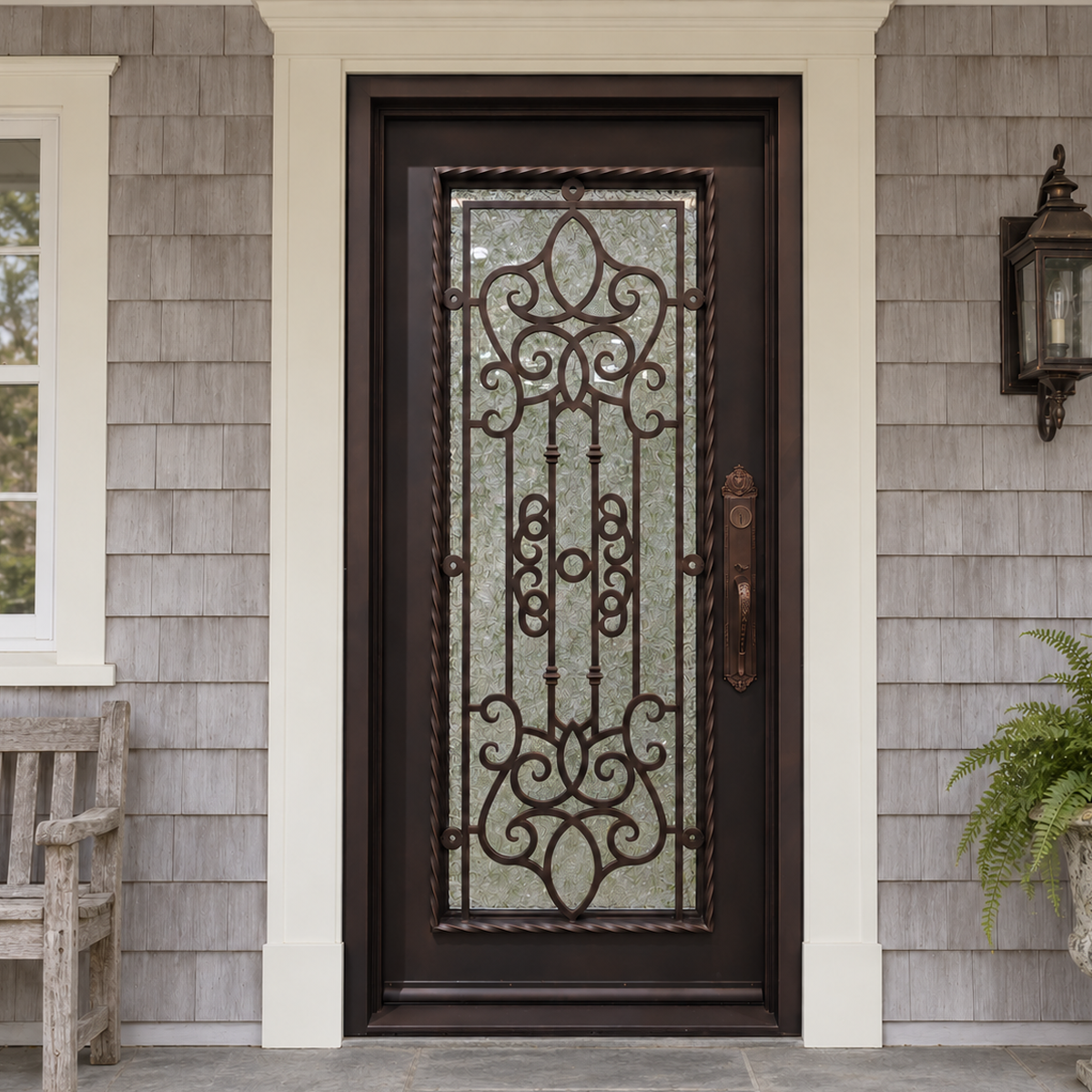 Bronze-toned single traditional iron door with ornate scrollwork and textured glass at a shingle-clad home entrance